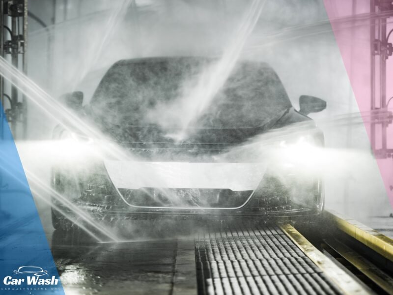 Close-up of a car undergoing a touchless car wash, with high-pressure water jets creating a misty veil around the vehicle's front, accentuating its headlights and sleek design, with the Car Wash Near Me logo at the bottom indicating the service provider.
